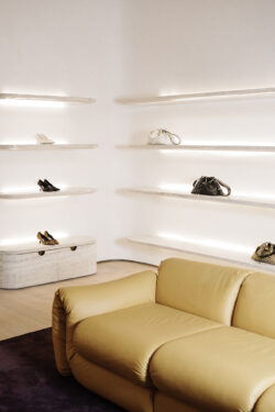 Interior of Jimmy Choo store showing shoes, bags and a couch.