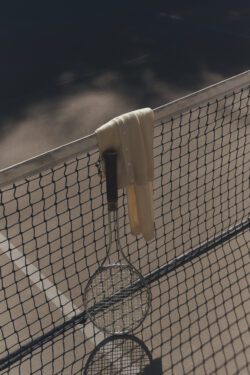 Paige cream sweater drapped over tennis net and next to tennis racket