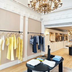inside Cami nyc boutique clothing on racks, center table with clothing, chandelier.