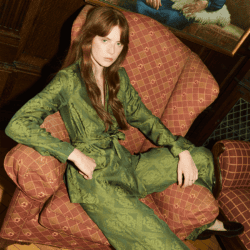 model wearing green tanya taylor pant suit sitting on red chair