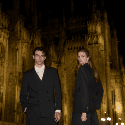 male and female model wearing black Giorgio Armani coats in front of church