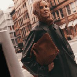 model wearing black Lafayette 148 leather jacket and brown sude bag in city street