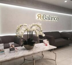 Rebalance Waiting room with black sofa, white coffee table white flowers.