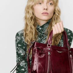 Model wearing floral blouse and holding burgandy purse from Zadig & Voltaire
