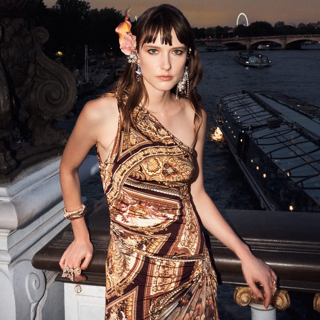 Model wearing Camilla black gold dress on a bridge